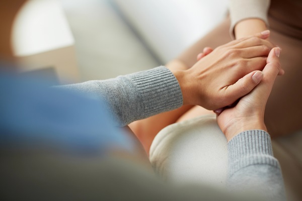 Hands clasped in support for coping with stress during Brisbane clinical psychology session